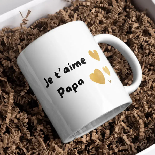 Mug en céramique blanche avec texte noir « je t’aime papa » et stickers en forme de cœur dorés.